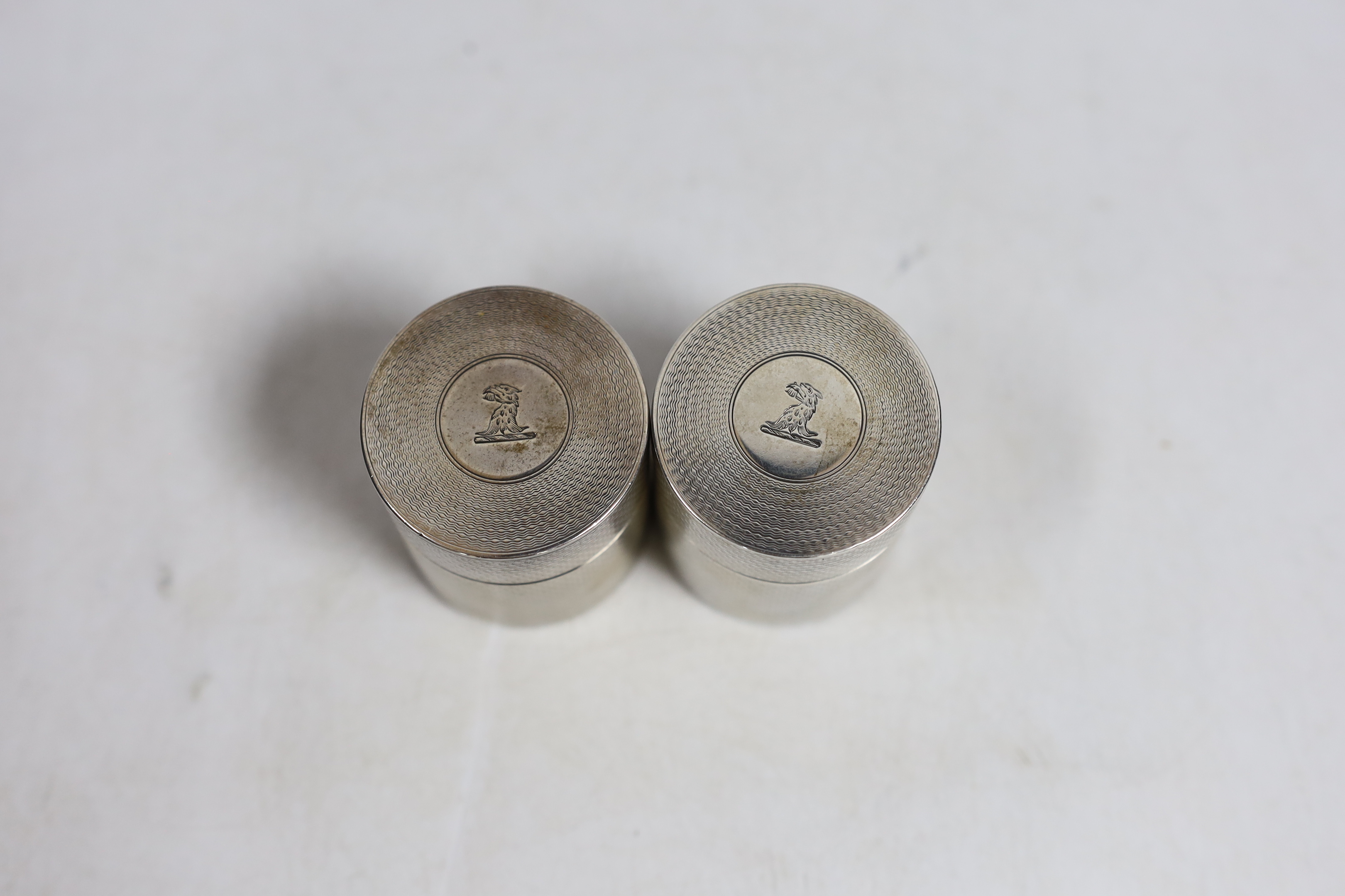 A George V engine turned silver cylindrical travelling inkwell?, by Samson Mordan & Co, London, 1910 with ribbed base and one other similar cylindrical box and cover, same date and maker, both with engraved crest, 48mm a